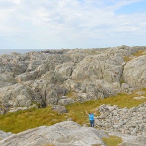 A photo of a tiny Asena Goren standing in a large rocky landscape.